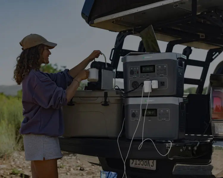 A woman uses a portable power station to power a kettle outdoors